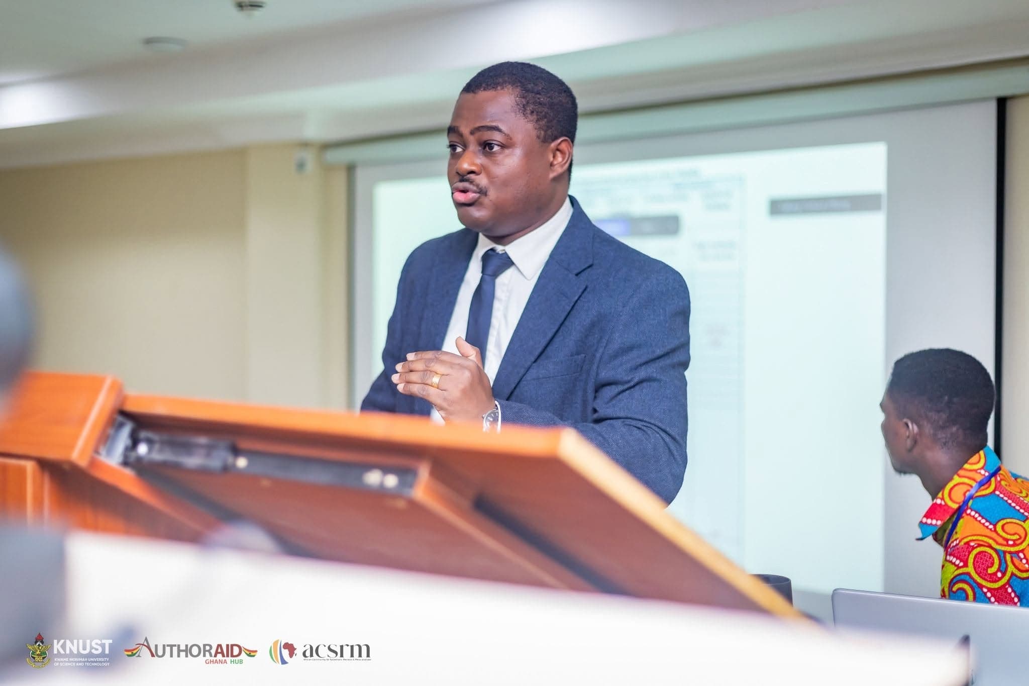 A facilitator speaking at a lectern during a systematic review workshop.